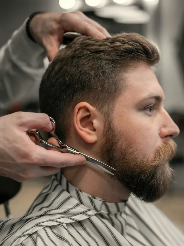 Barbeiro aparando a barba do cliente na tesoura