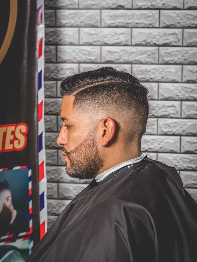 Mid fade: degradê médio com risca marcada e barba desenhada